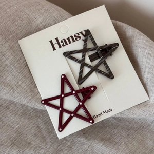 Detail view of two star-shaped hair clips with polka dots and stripes on a card