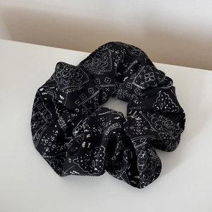 Detailed macro view of a large black paisley print scrunchie with soft fabric texture