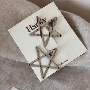 Detailed view of two star-shaped hair clips with polka dots and stripes on a display card