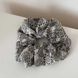 Macro shot of oversized white scrunchie with classic black paisley floral patterns
