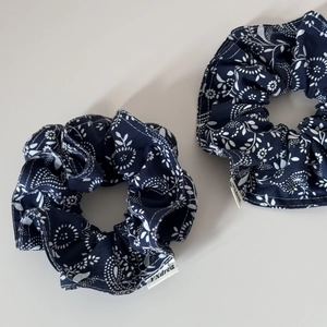 Detail showing the fine floral print and fabric texture of the navy blue scrunchies