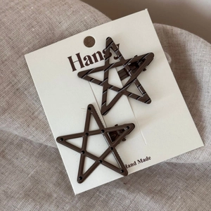 Close-up of brown star hair clips with polka dots and stripes on white card
