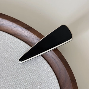 Détail macro d'une pince à cheveux triangulaire noire avec bordure argentée sur bois
