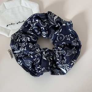 Detail of navy blue floral scrunchie with white flower patterns and woven side label
