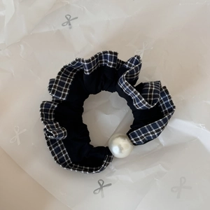 Close-up of black retro scrunchie with blue plaid lace trim and large faux pearl detail
