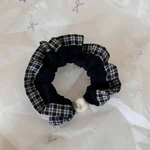 Detail of plaid lace scrunchie featuring vintage pearl embellishment on textured fabric