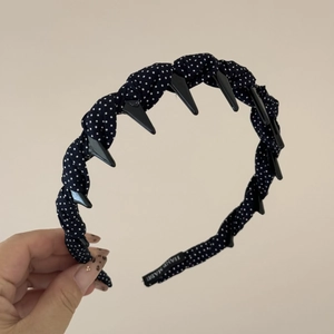 Détail d'un serre-tête en tissu à pois vintage avec dents antidérapantes et étiquette fait main
