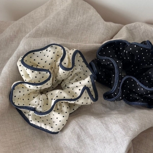 Detailed view of polka dot satin scrunchies with denim edge on linen background