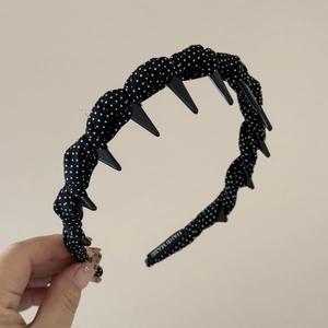 Détail d'un serre-tête à pois noirs avec peigne intérieur et étiquette tissée Hand Made
