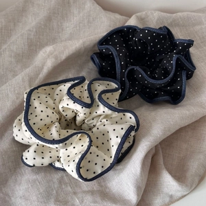 Close-up of black and white polka dot scrunchies with denim blue stitched edges
