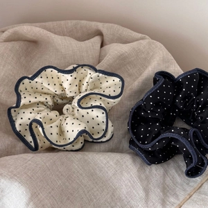 Close-up of polka dot satin scrunchies in black and cream with denim wave edges