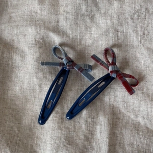 Gros plan détaillé de barrettes à nœud en tissu écossais rouge et bleu sur lin