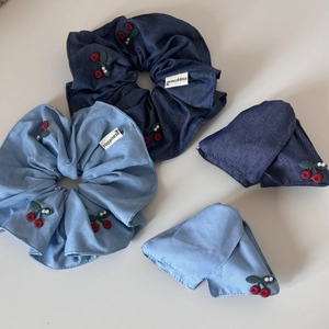 Close-up of denim cherry hair scrunchies and bow clips with embroidery and pearls