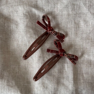 Détail de barrettes à cheveux avec nœud en tissu à carreaux rouges et base marron