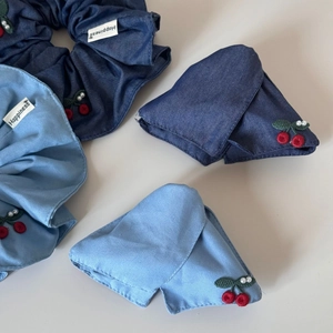 Detail of embroidered cherries and Happiness label on denim bow hair clip and scrunchie