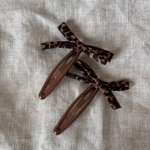 Paire de barrettes à nœud imprimé léopard sur un fond en tissu de lin texturé
