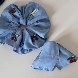Denim bow hair claw clip with red cherry embroidery and pearl accents on white background