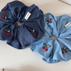 Detail of denim hair scrunchies with red cherry embroidery and white pearls