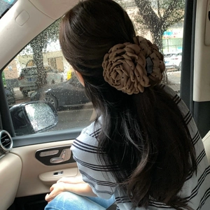 Elegant khaki leopard dot rose flower hair claw clip worn by woman in car setting
