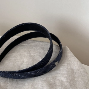 Detail of dark blue plaid headbands with a small silver heart-shaped metal accent