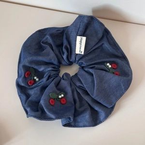 Detail of denim blue scrunchie with red cherry embroidery and white pearl accents