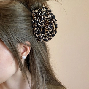 Macro side view of a layered leopard print fabric rose flower claw clip on hair