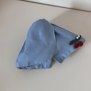 Close-up of red cherry embroidery and pearl beads on light blue denim fabric hair clip