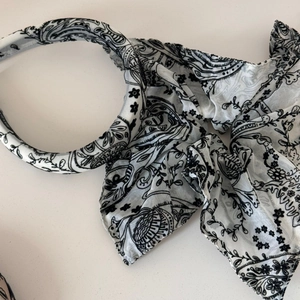 Detail of vintage paisley floral fabric pattern on a white satin-finish headband accessory