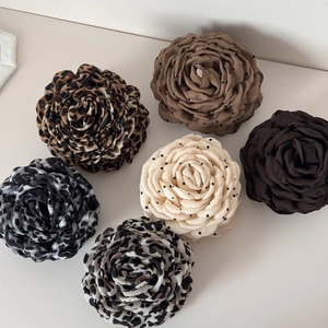 Detail of six floral hair claws with leopard prints, polka dots, and soft fabric textures