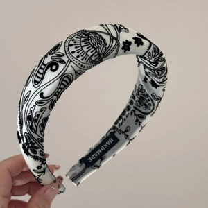 Detailed macro view of black and white floral pattern fabric headband with handmade label