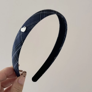 Detail of plaid fabric headband with silver heart charm and matte inner lining texture