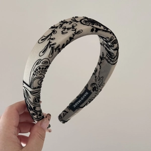 Detailed macro view of cream-colored floral headband featuring a black handmade woven label