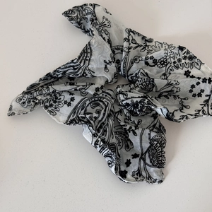 Close-up of a black and white paisley floral chiffon hair scrunchie with long ribbons