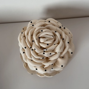 Detailed macro view of a fabric rose hair claw clip with classic black polka dots on beige