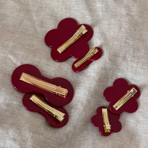 Detailed back view of six burgundy acetate hair clips with golden metal duckbill fasteners