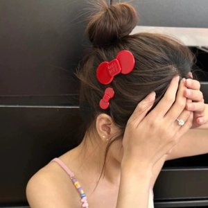 Detail of red acetate bow hair clips in large and small sizes worn by a model