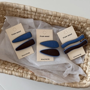 Détail de barrettes à cheveux en tricot bleu denim et marron dans un panier en osier