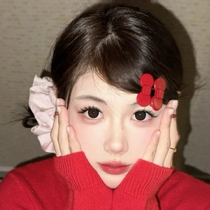 Detail showing a red bow hair clip and pink scrunchie on model for styling reference