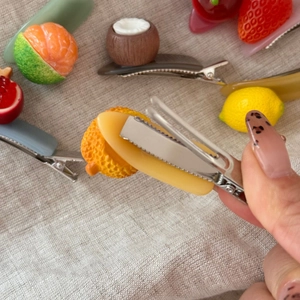 Close-up of fruit hair clip showing the silver metal duckbill clip and resin detail