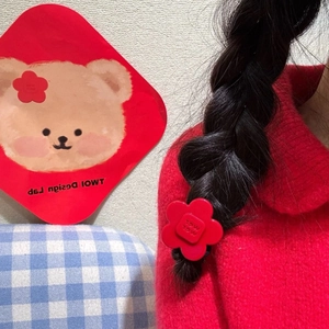 Vibrant red flower acetate hair tie with MGL engraving on a braided hairstyle