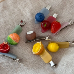 Detail shot of assorted resin fruit hair clips featuring realistic food models on metal pins