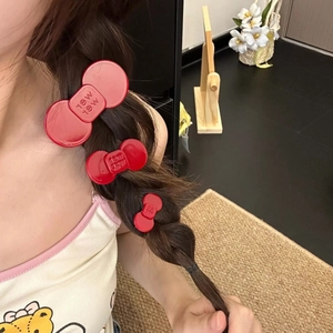 Three red glossy bow hair clips with lettering shown on side braid hairstyle