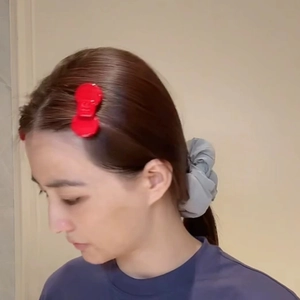 Detail of red bow hair clip with luxury logo and soft grey fabric hair scrunchie set