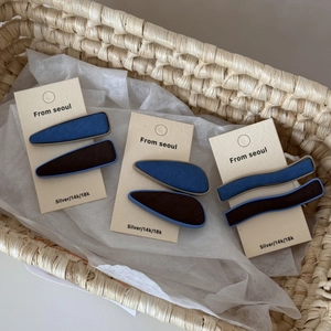 Détail de barrettes vintage en tissu bleu denim et marron sur une carte support