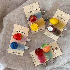 Macro detail of various fruit-shaped acetate hair clips with vibrant resin designs