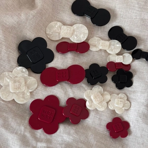 Close-up of acetate flower and bow hair clips with marbled texture and engraved letters