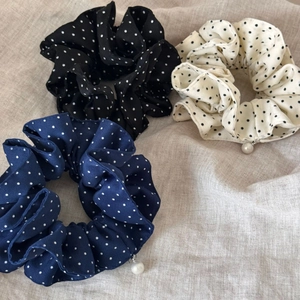 Detailed view of three polka dot fabric scrunchies with elegant pearl pendants in various colors