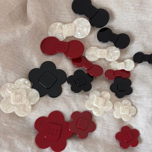 Detailed view of acetate flower and bow hair clips with brand engraving on linen texture