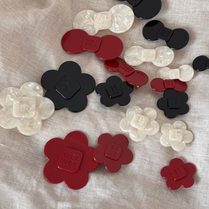 Flat lay of acetate flower and bow hair clips with embossed wer wer letter details