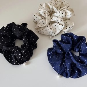 Detailed view of polka dot scrunchies in three colors with pearl pendants on white background